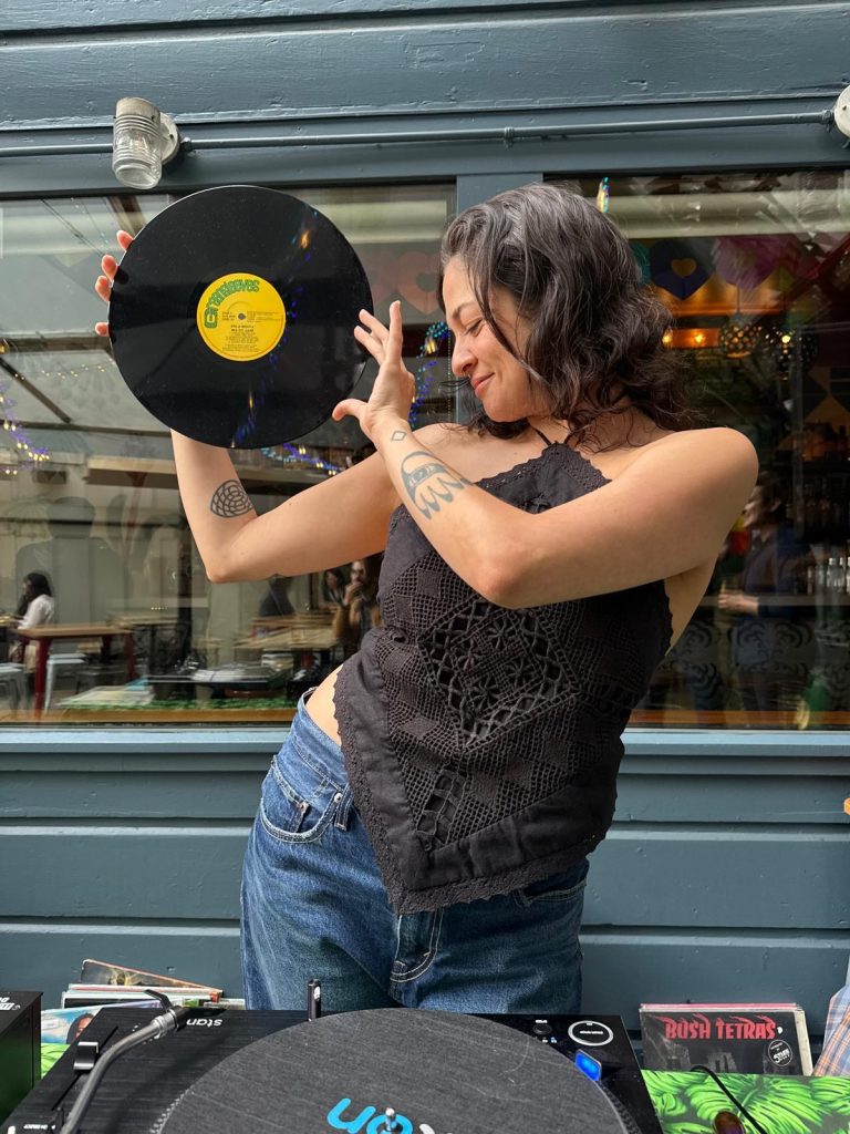 DJ Little Sister holds and LP up for the crowd to admire.